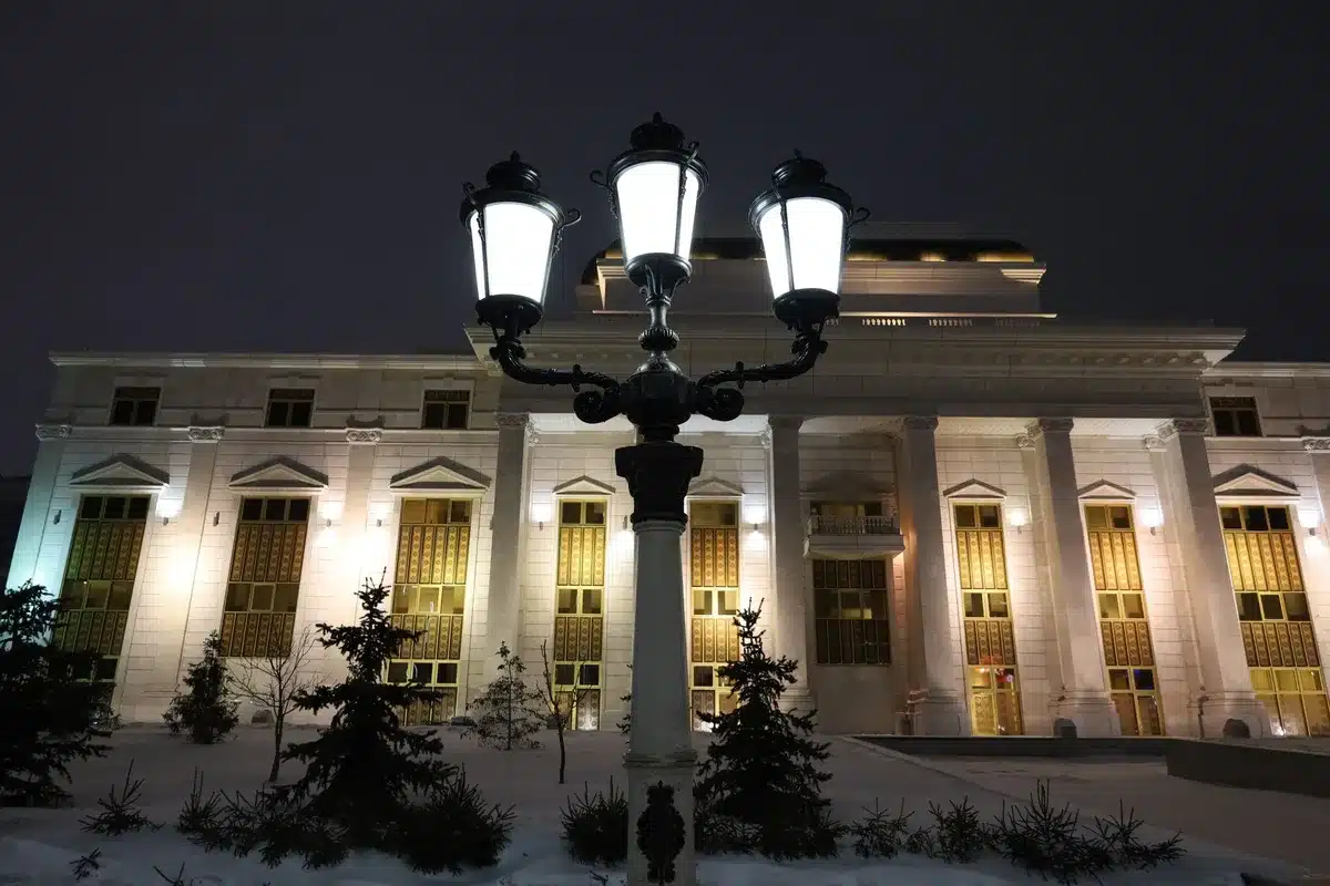 Capitol building exterior at dusk with American flag, Senate chamber dome illuminated, empty plaza, overcast sky suggesting legislative stalemate