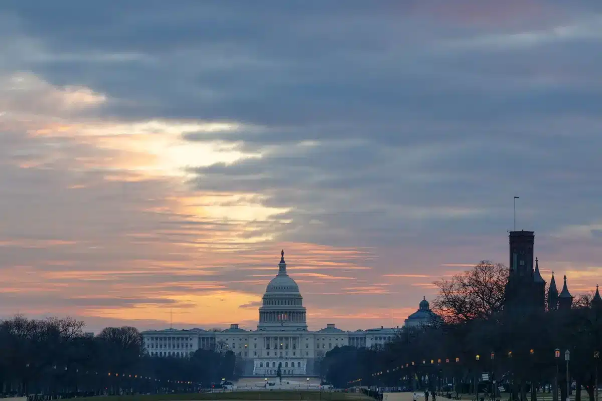 Capitol building exterior at dusk with storm clouds gathering overhead, architectural details sharp against darkening sky