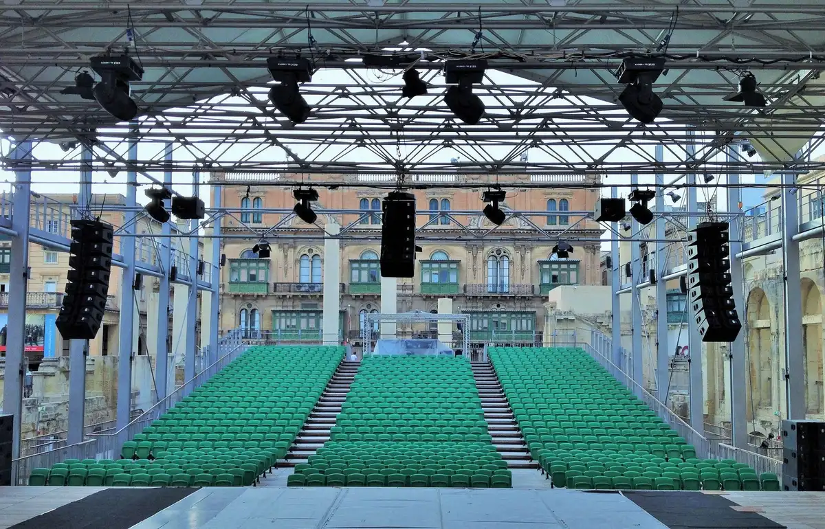 An empty campaign rally stage with a single microphone stand and scattered campaign signs in the background