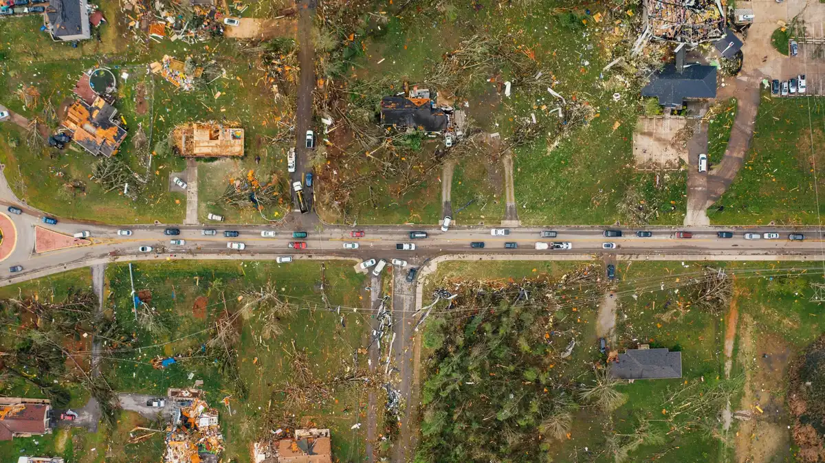 Six-vehicle pileup aftermath on highway, smoke and emergency vehicles, charred vehicles, daylight, interstate setting, tragic scale