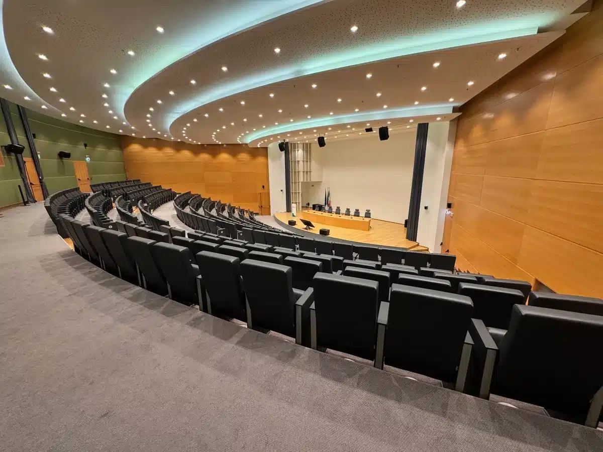 A grand palace conference room with empty chairs arranged formally, sunlight streaming through tall windows, casting long shadows across a polished wooden floor, evoking diplomatic negotiation and historical consequence.