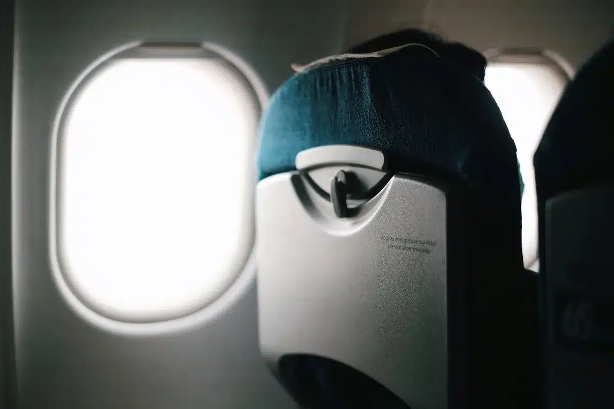 Interior of an aircraft cabin with closed window shades, empty rows of seats, dim lighting, a sense of security protocols in place