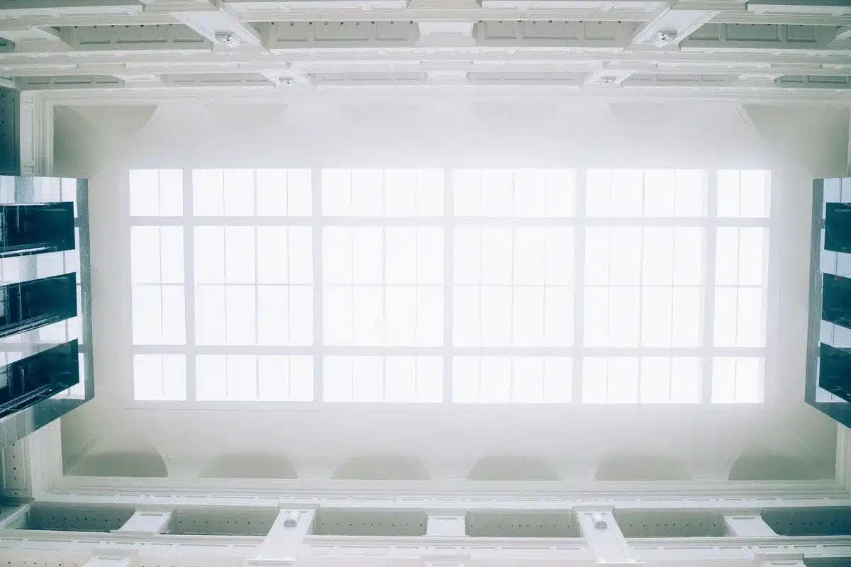 A courthouse interior with empty judge's bench and witness stand, soft natural light through tall windows, no people visible