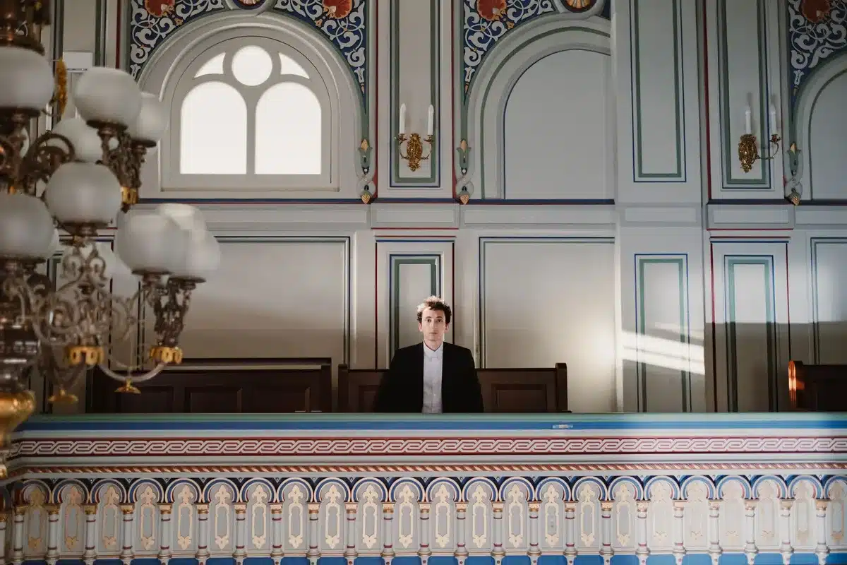 A federal courthouse corridor with tall columns and dim lighting, a lone gavel on an empty judge's bench, formal legal documents stacked on a wooden table