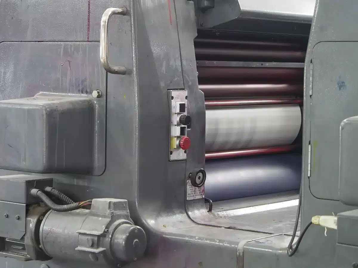 A newspaper printing press in motion, pages flowing through metal rollers, blurred text on newsprint, a single page caught mid-air