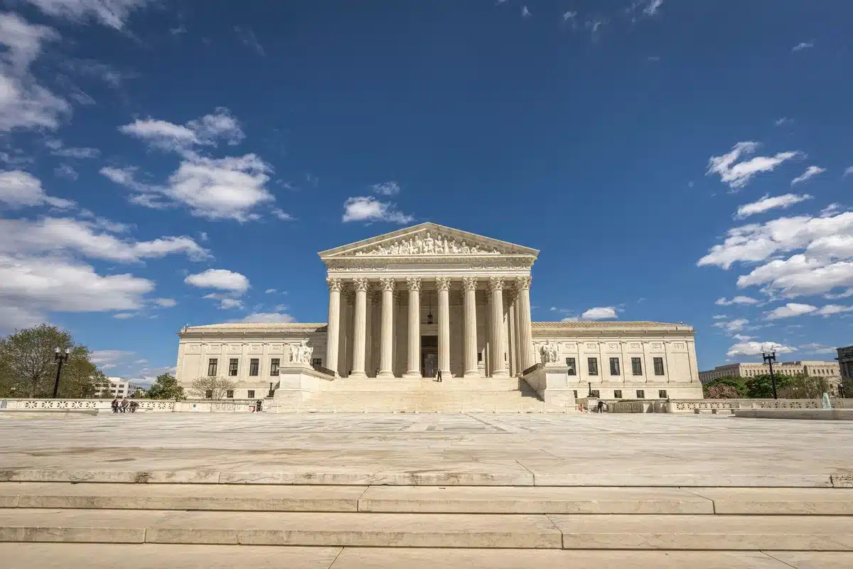 A marble-columned federal courthouse entrance with autumn light casting shadows, symbolic scales of justice visible in the foreground, an empty hallway beyond