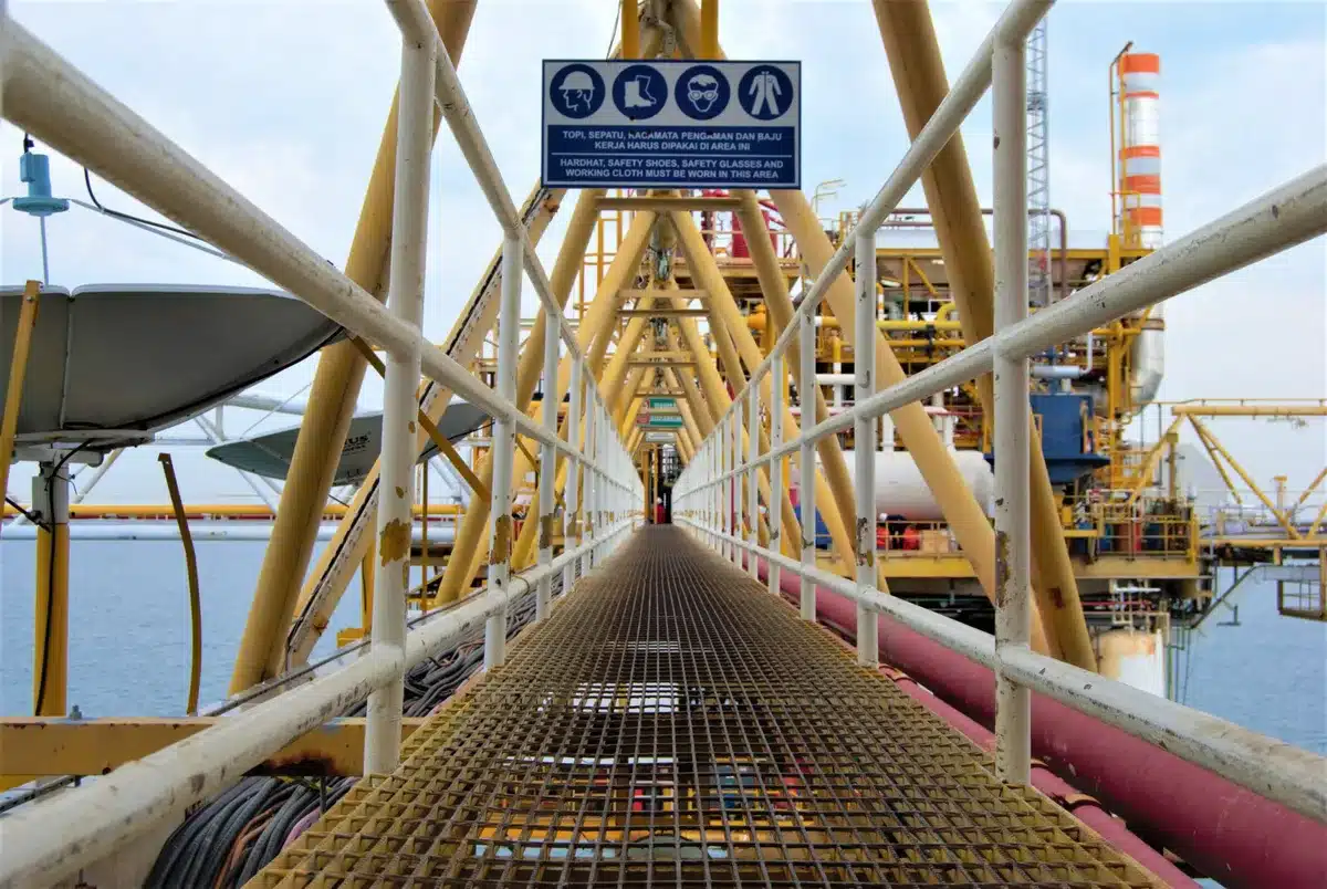 A Venezuelan oil field with multiple derricks and pump jacks positioned across industrial landscape under clear sky, industrial equipment and pipelines visible, representing vast energy resources