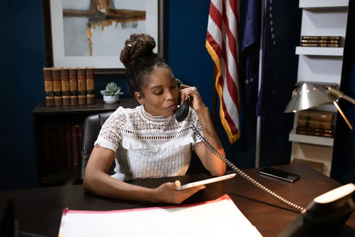 A formal boardroom with an empty chair at the head of a polished conference table, a telephone on the desk, sunlight streaming through tall windows overlooking a city skyline, symbolic of high-stakes economic decision-making