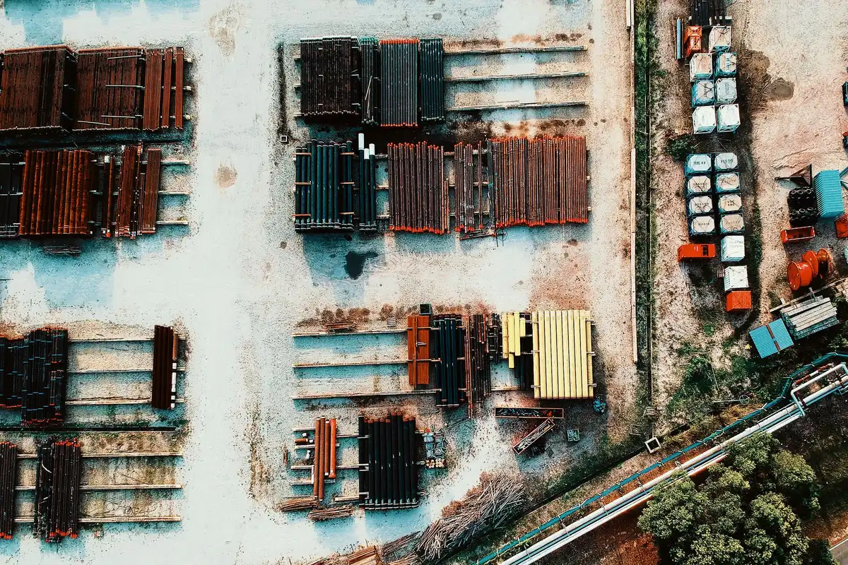 A close-up of construction materials stacked at a federal building site&mdash;steel beams, concrete blocks, and architectural plans rolled on a table&mdash;with federal seals or official signage visible in soft focus