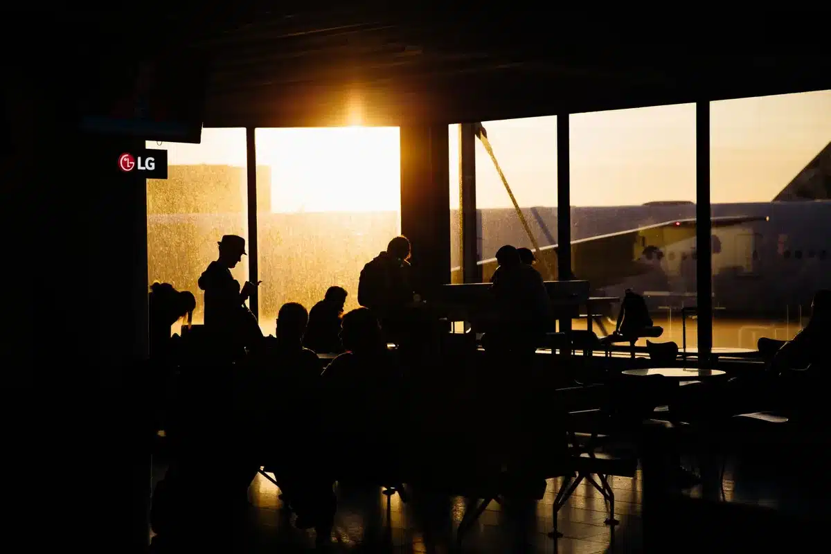 Modern airport gate area with flight information displays, aircraft visible through windows, United Airlines branding, regional passengers preparing to board