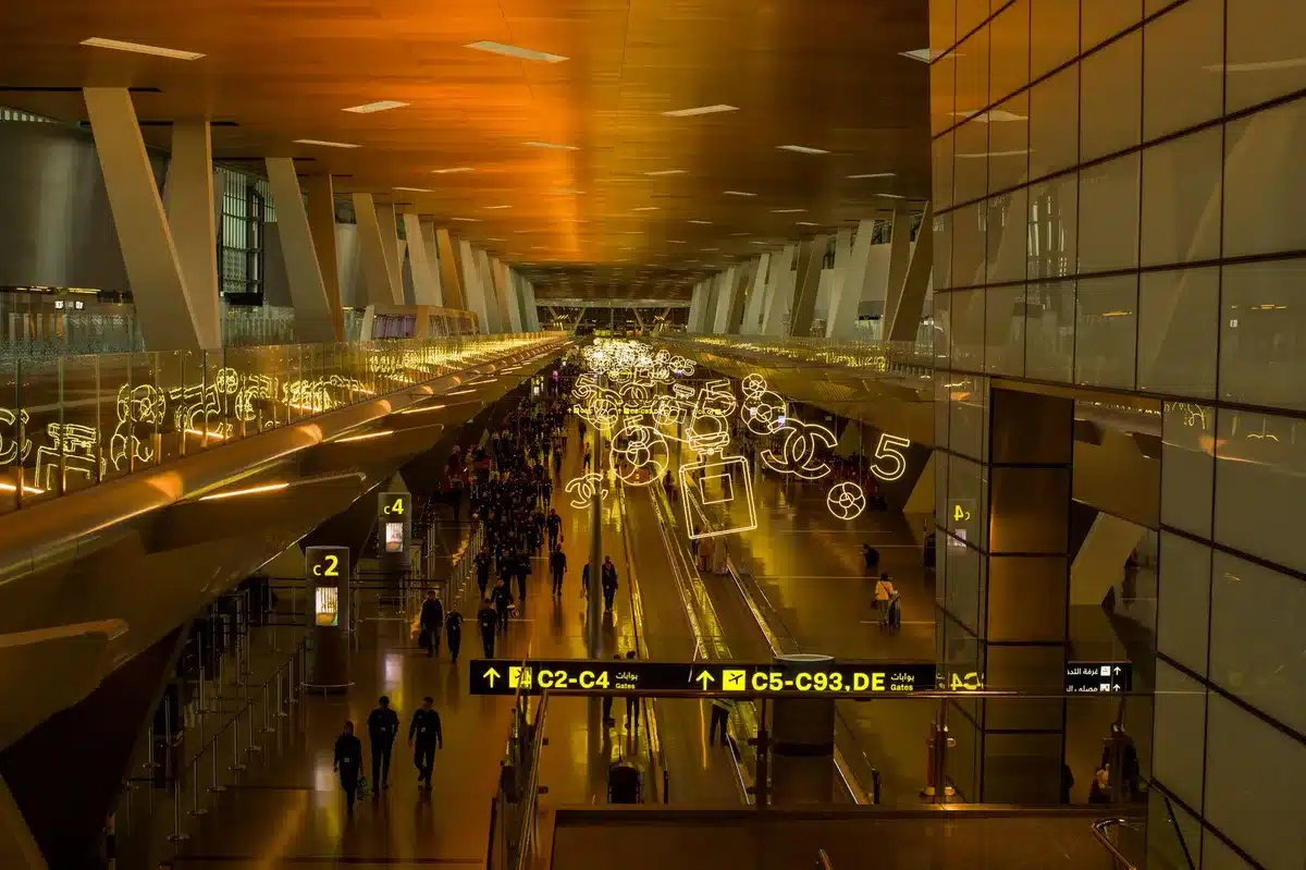 A quiet airport terminal corridor with large windows framing a dawn sky, morning light streaming across empty gates and seating areas, a sense of anticipation before the day begins.