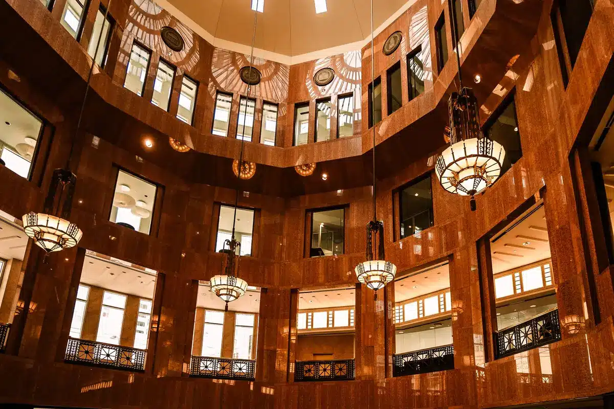 A federal courthouse interior with marble columns and judicial seals, sunlight streaming through tall windows, conveying institutional authority and legal process.