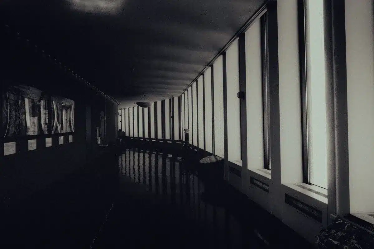 An empty federal courthouse hallway with marble columns, a gavel visible on a judge's bench in soft focus, symbolizing legal challenge and judicial restraint.