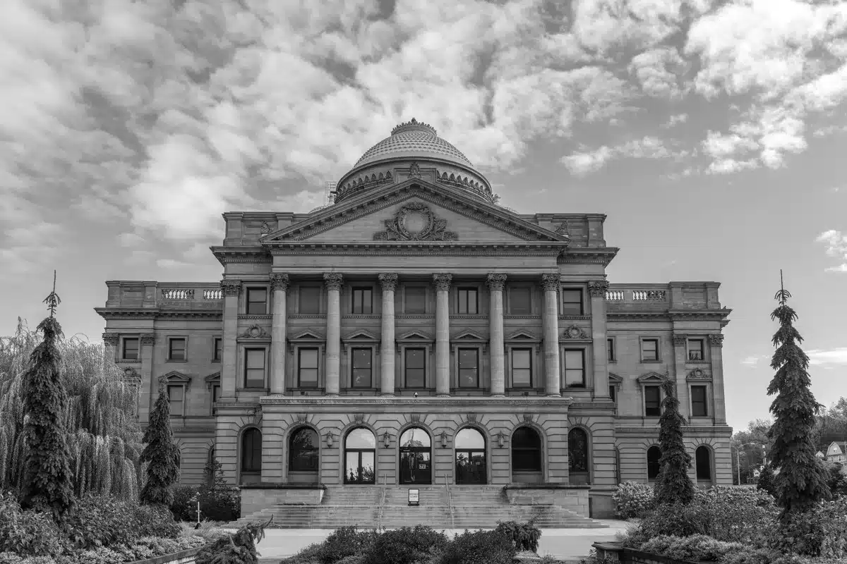 A federal courthouse entrance with columns and steps, early morning light casting long shadows, suggesting legal proceedings and judicial authority