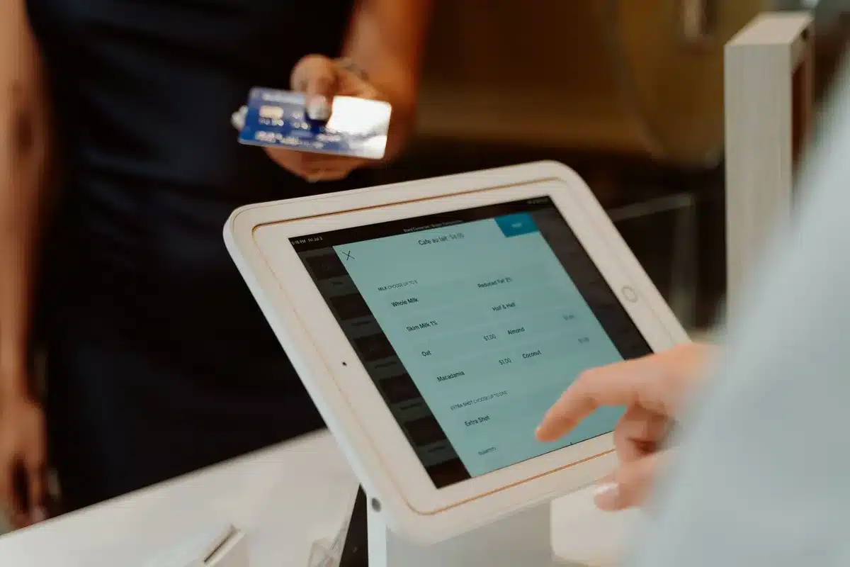 Anonymous customer's hand holding a smartphone near a modern contactless payment terminal at a retail checkout counter, the screen glowing with payment confirmation, minimalist store environment with soft lighting