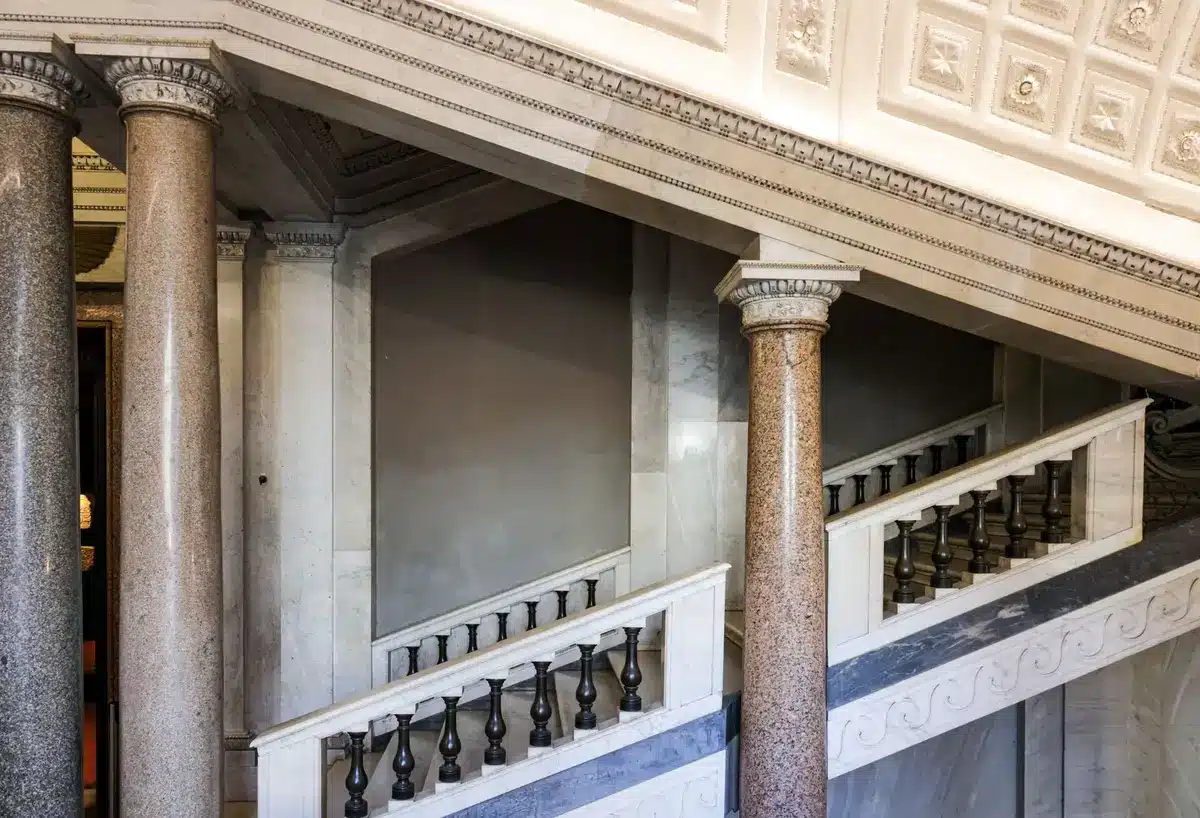 Empty courtroom with mahogany paneling, a single gavel on the judge's bench, soft light filtering through tall windows, suggesting the weight of legal proceedings