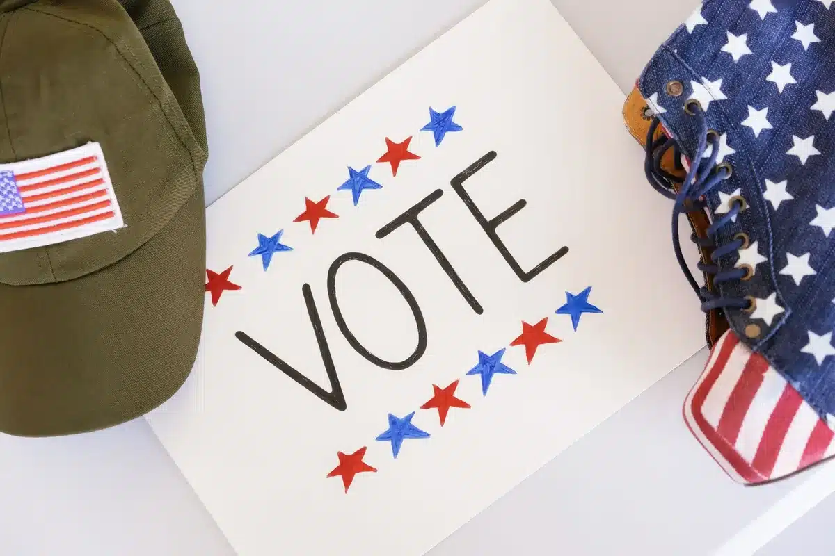 A ballot box with voting materials, hands inserting a ballot, soft indoor lighting, neutral background