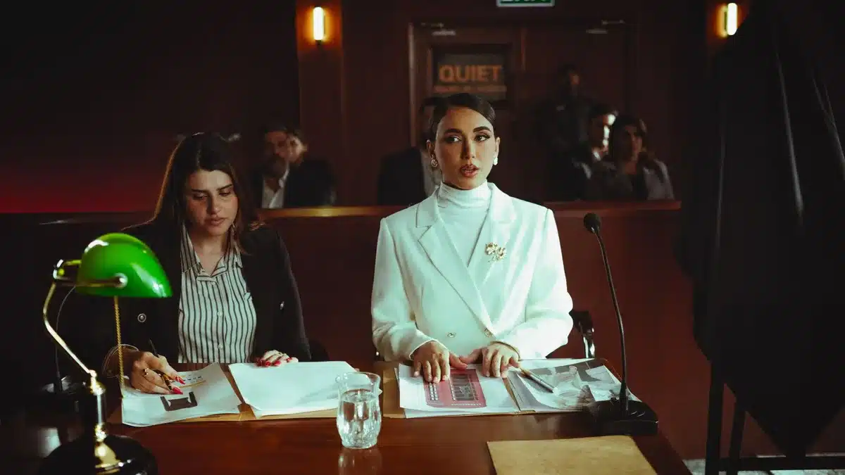 A split-screen courtroom scene with opposing empty chairs, harsh fluorescent lighting casting shadows, papers scattered on a wooden table, tension in the sterile atmosphere