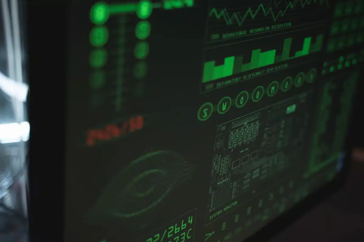 A glowing computer screen displaying financial data dashboards with AI-powered analytics charts and metrics in soft blue and green light, a hand holding a pen poised over a notebook beside the screen, suggesting enterprise decision-making powered by AI