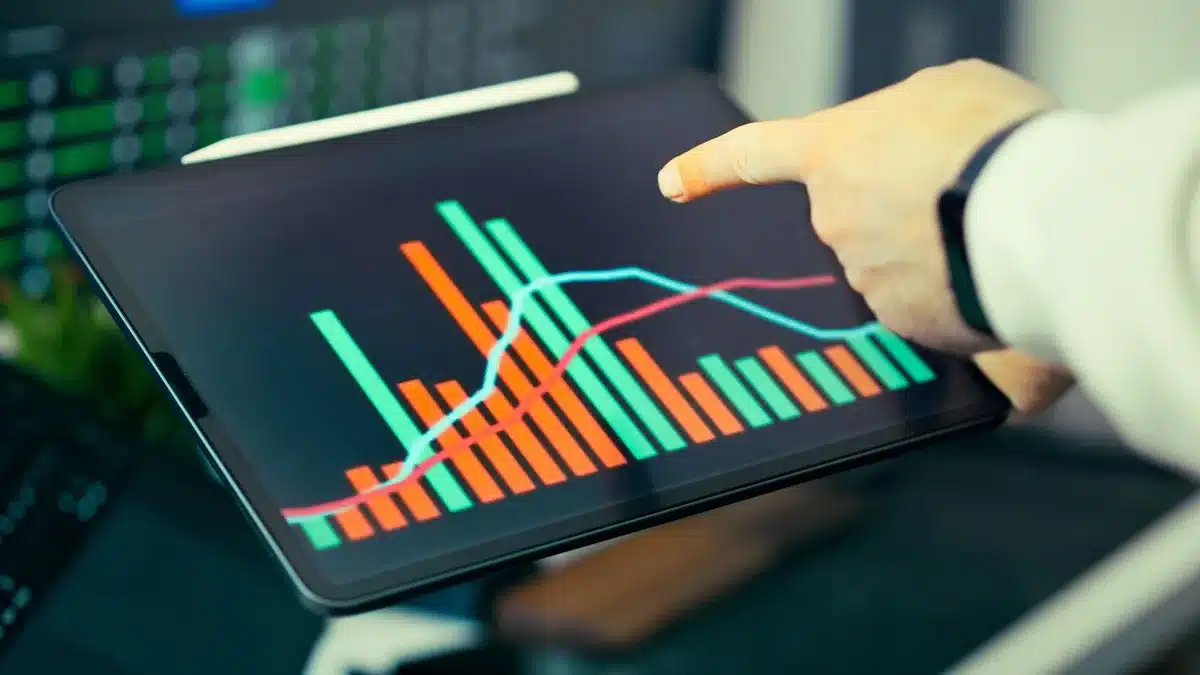 Modern office workspace with multiple computer monitors displaying business analytics dashboards and charts, focused on data visualization screens, soft daylight from windows
