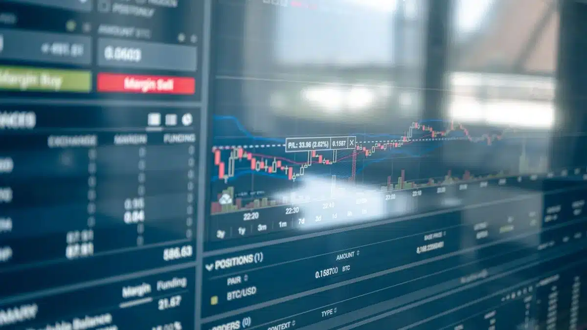 A digital asset price chart showing a sharp downward trend line crossing below a horizontal support level, red candlesticks dominating the display, a glowing screen in dim light