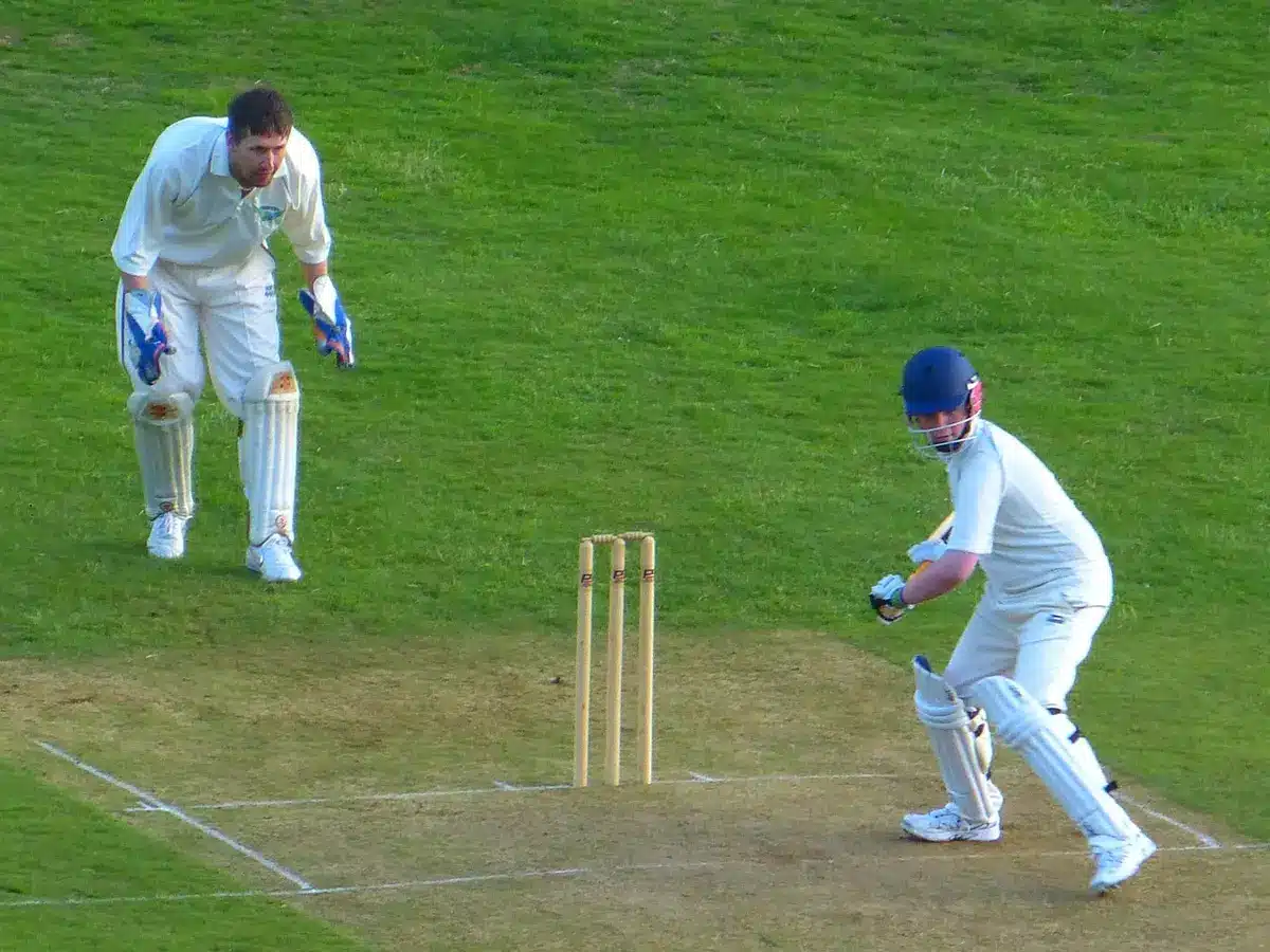 Two anonymous players' gloves and a ball left on the boundary rope, empty stands behind, evening light