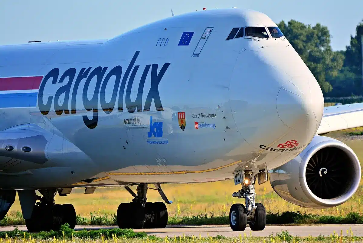 An empty tarmac at an international airport with a massive Boeing 747 jet parked under dramatic sky, its white fuselage gleaming against storm clouds, ground crew and security vehicles distant, suggesting presidential-grade security and international travel preparation