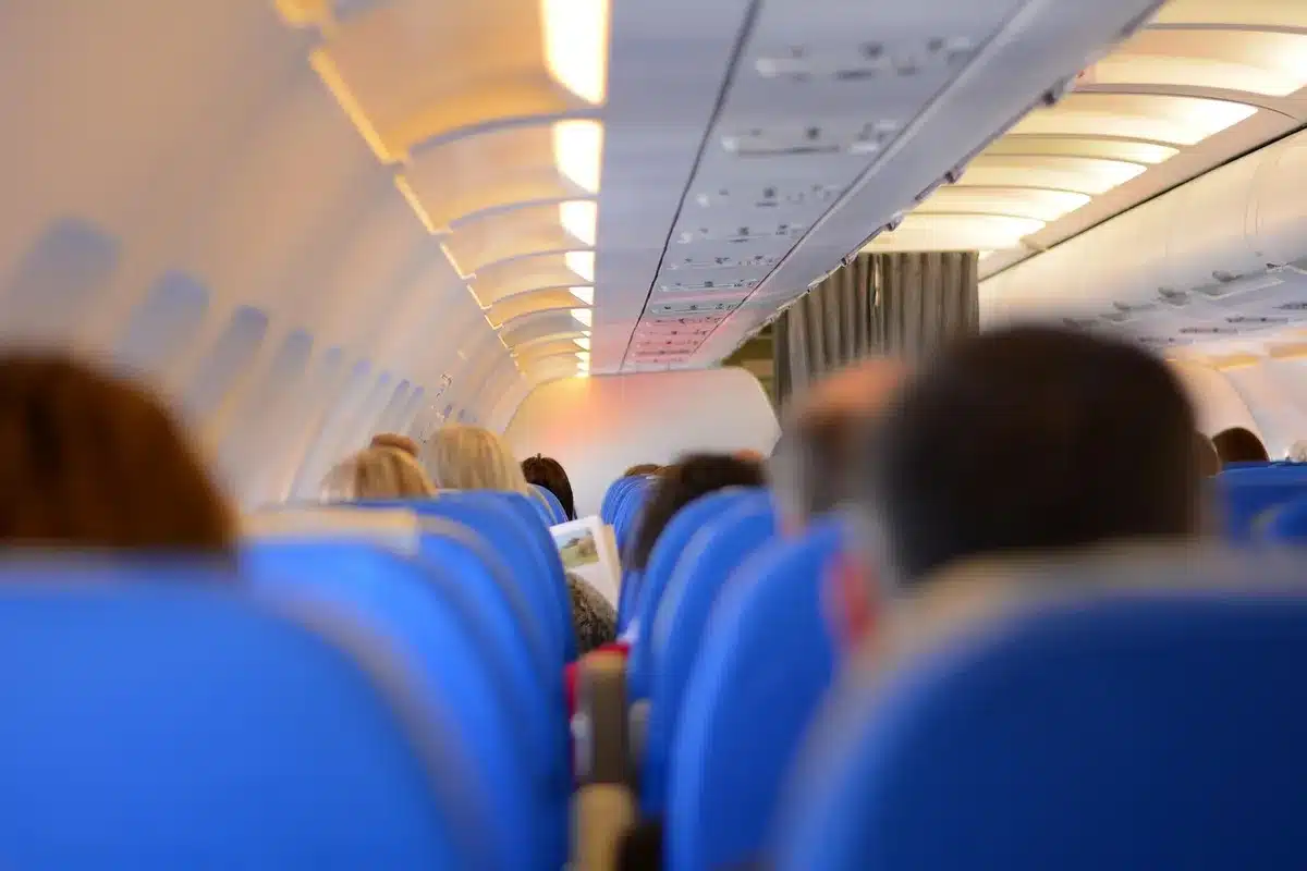 A retrofitted wide-body aircraft cabin interior, showing rows of sleek business-class seats with privacy doors and modern design elements, passengers boarding or settling in, cabin lighting highlighting the premium finishes