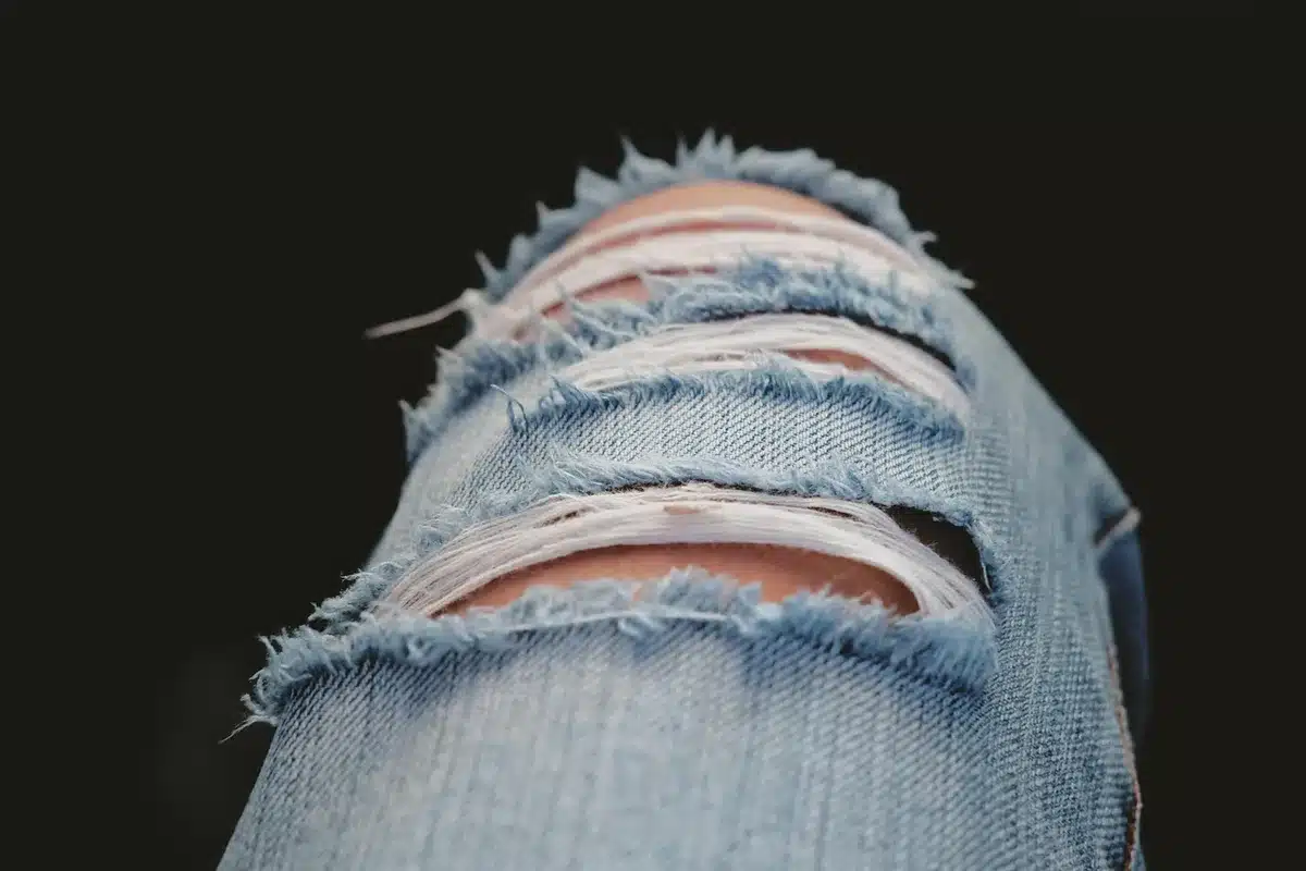 Oversized denim garments and cargo pants laid out on a neutral surface, showing relaxed silhouettes and utility details, streetwear styling aesthetic