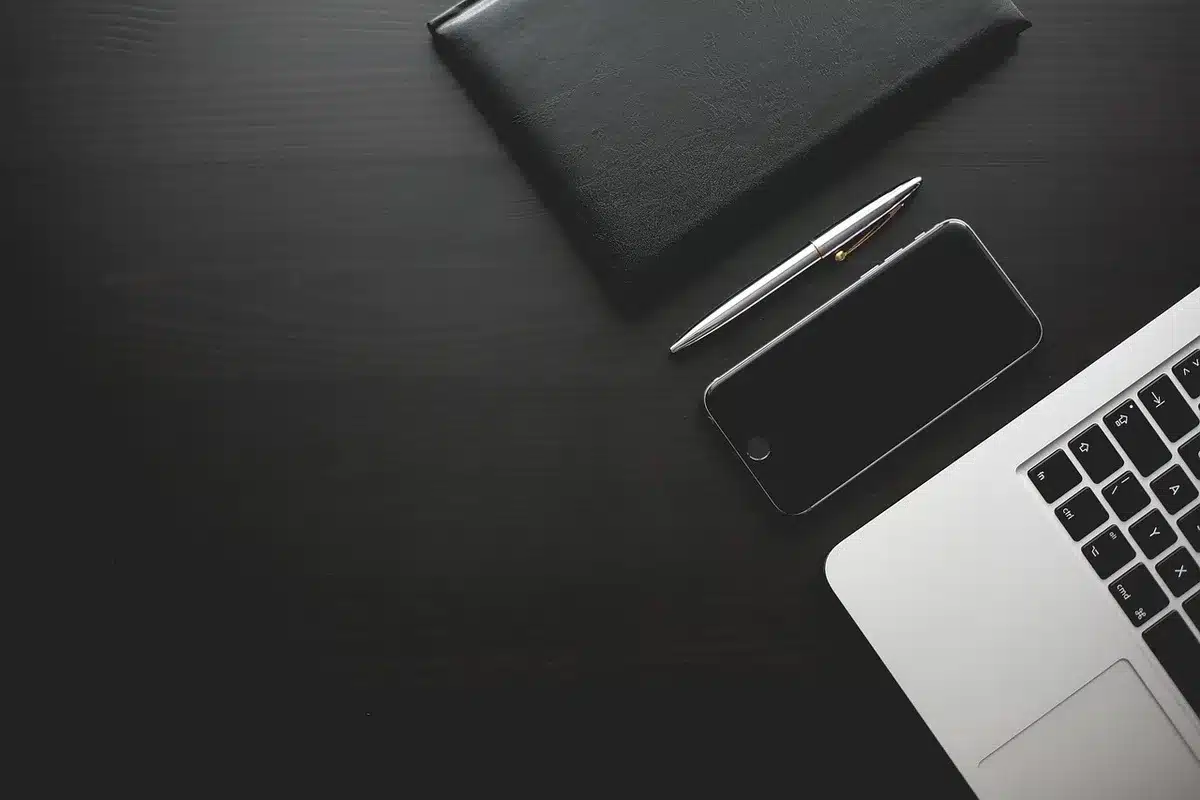 A close-up of an unbranded folded smartphone resting on a dark table, the inner screen partially visible and glowing with abstract icons