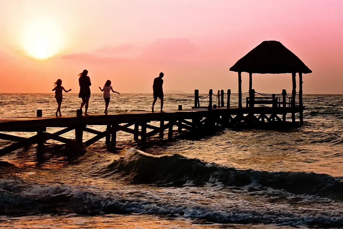 A diverse group of families with children walking together outdoors, viewed from behind, moving toward a bright horizon, symbolizing citizenship and belonging.