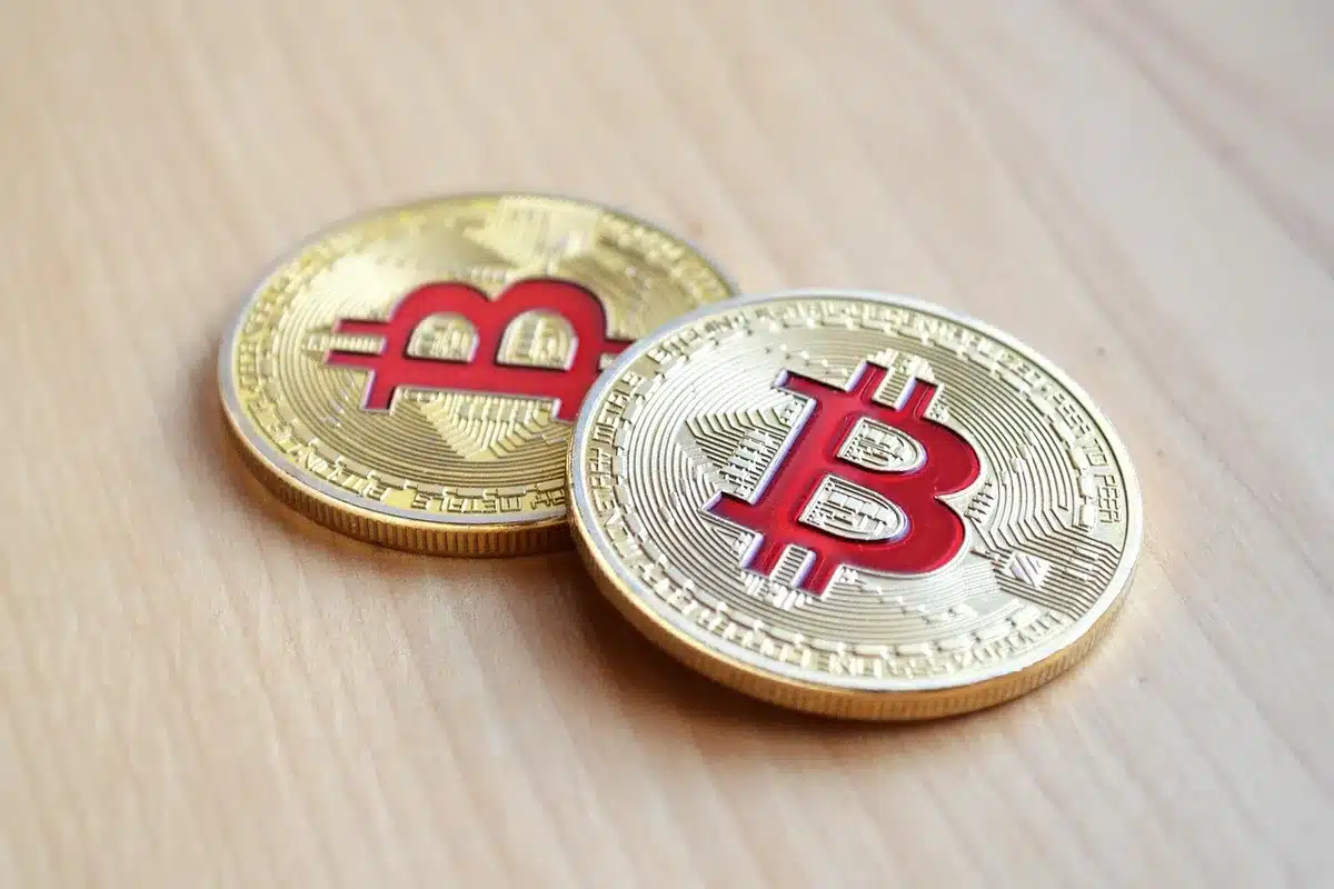 A symbolic scene of an anonymous stack of generic gold coins beside a plain ledger and a pen on a wooden table, hinting at store-of-value themes