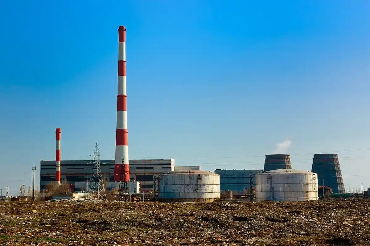 A glowing fuel cell stack beneath industrial lighting, steam rising from vents, generic data center architecture in soft focus behind it, clean energy infrastructure aesthetic