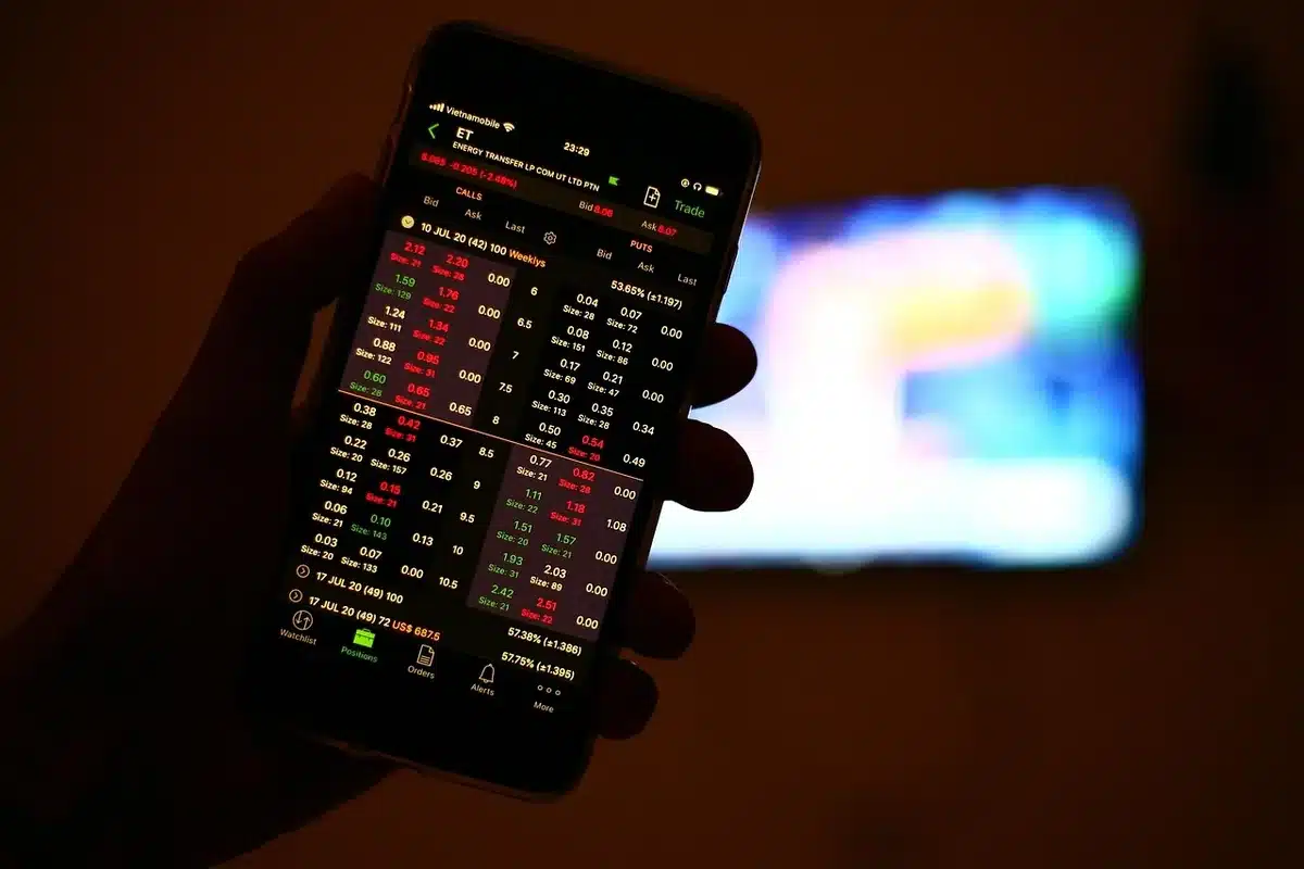 Anonymous silhouette of an investor looking at a trading screen showing falling lines, hands on chin, low light suggesting concern and reflection
