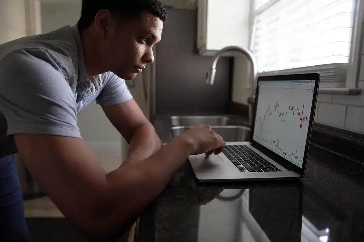 A glowing stock price chart on a dark screen with upward-trending candlesticks and green numbers, a hand holding a smartphone displaying portfolio gains, soft blue and green lighting