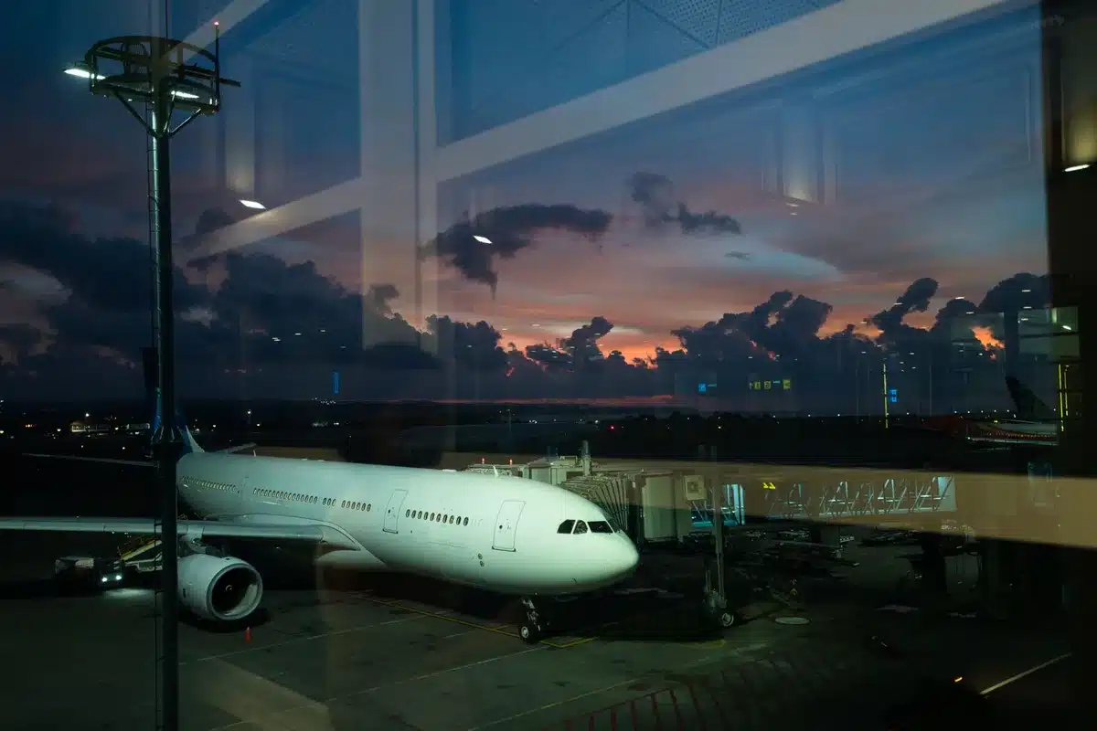 An empty airport gate with a single unattended pushback tug and a closed jet bridge under overcast light, no airline logos visible