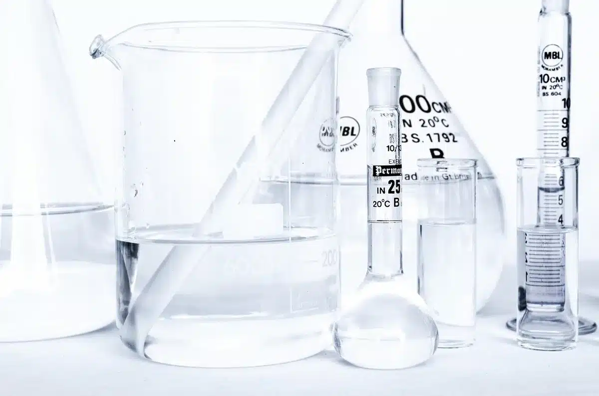 Scientific laboratory setting with a glowing DNA helix model suspended in blue light, laboratory equipment and microscopes blurred in background, emphasis on the molecular structure