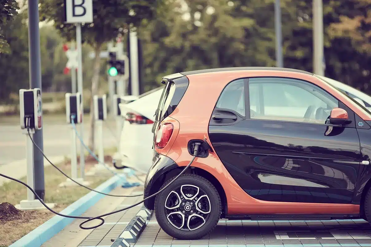Close-up of an anonymous EV charger island and a generic fuel pump canopy at dusk, no branding or signage visible
