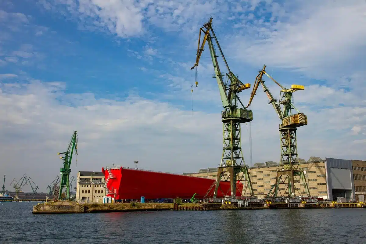 Aerial view of an anonymous shipyard slipway with several unbranded hulls in various stages of construction, cranes and scaffolding visible