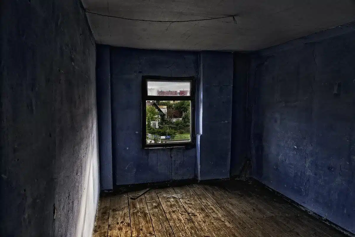 An empty cryptocurrency exchange trading floor at dusk, monitors dark or dimmed, a single abandoned trading station with chairs pushed back, ambient light from distant city windows, silence and absence