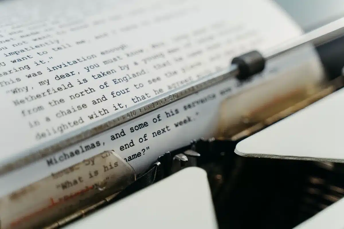 Close-up of anonymous hands holding a printed essay page headlined 'We Must Pace the Frontier', text blurred and unreadable, no logos or faces