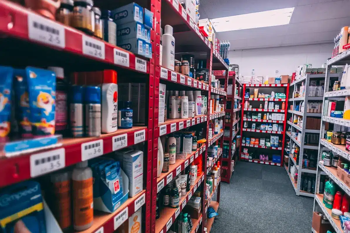 A generic store aisle with anonymous shoppers pushing carts, a price tag on a shelf visible in the foreground and a blurred checkout area in the background