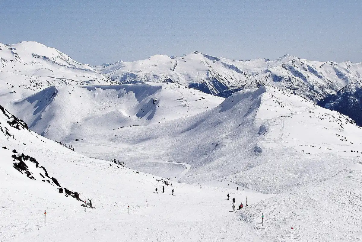 A freestyle skier in mid-air during a halfpipe run, body twisted mid-rotation, snow spraying, mountain backdrop blurred in motion, focus on the athlete's form and control.