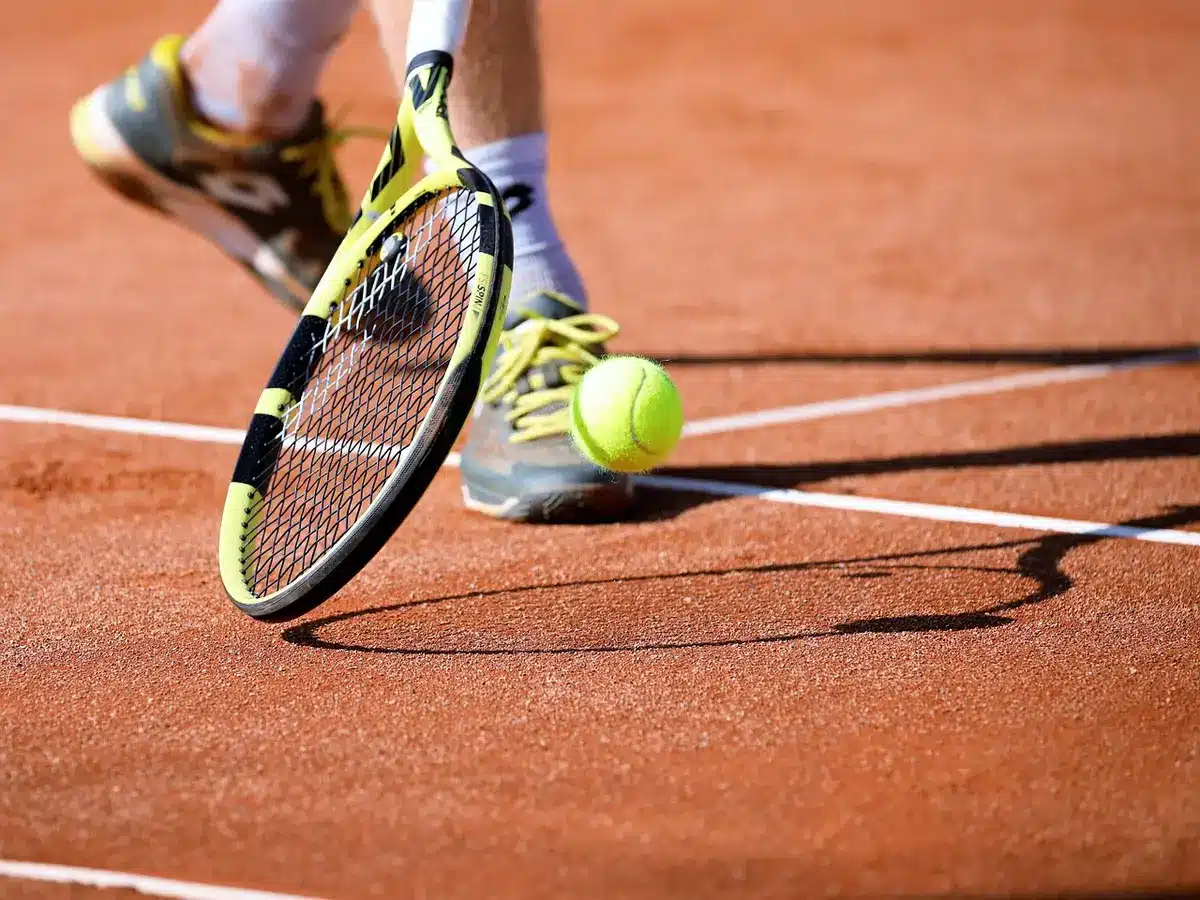 A quiet tournament practice court under floodlights, an empty chair and a folded tournament towel beside a racquet bag — tournament atmosphere without people