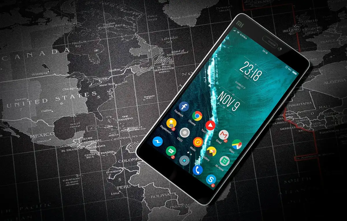 Anonymous hands holding a smartphone showing a generic crypto-price chart silhouette, away from the camera, with a blurred office background.
