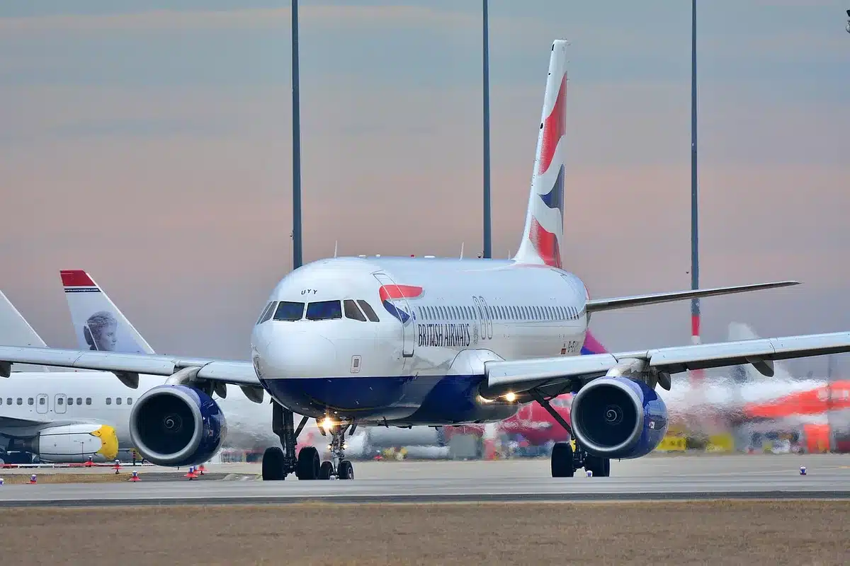 Close-up of an anonymous hand holding a smartphone with an unbranded flight-status app open showing a delayed departure and alternate flight suggestions