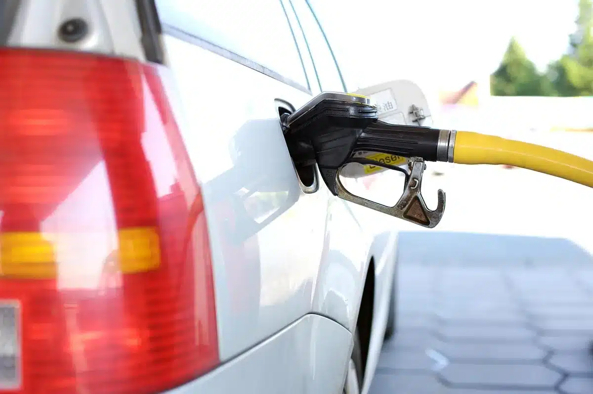 Close-up of an analog diesel pump nozzle resting on the pump, no logos visible, blurred gas station canopy behind — tension