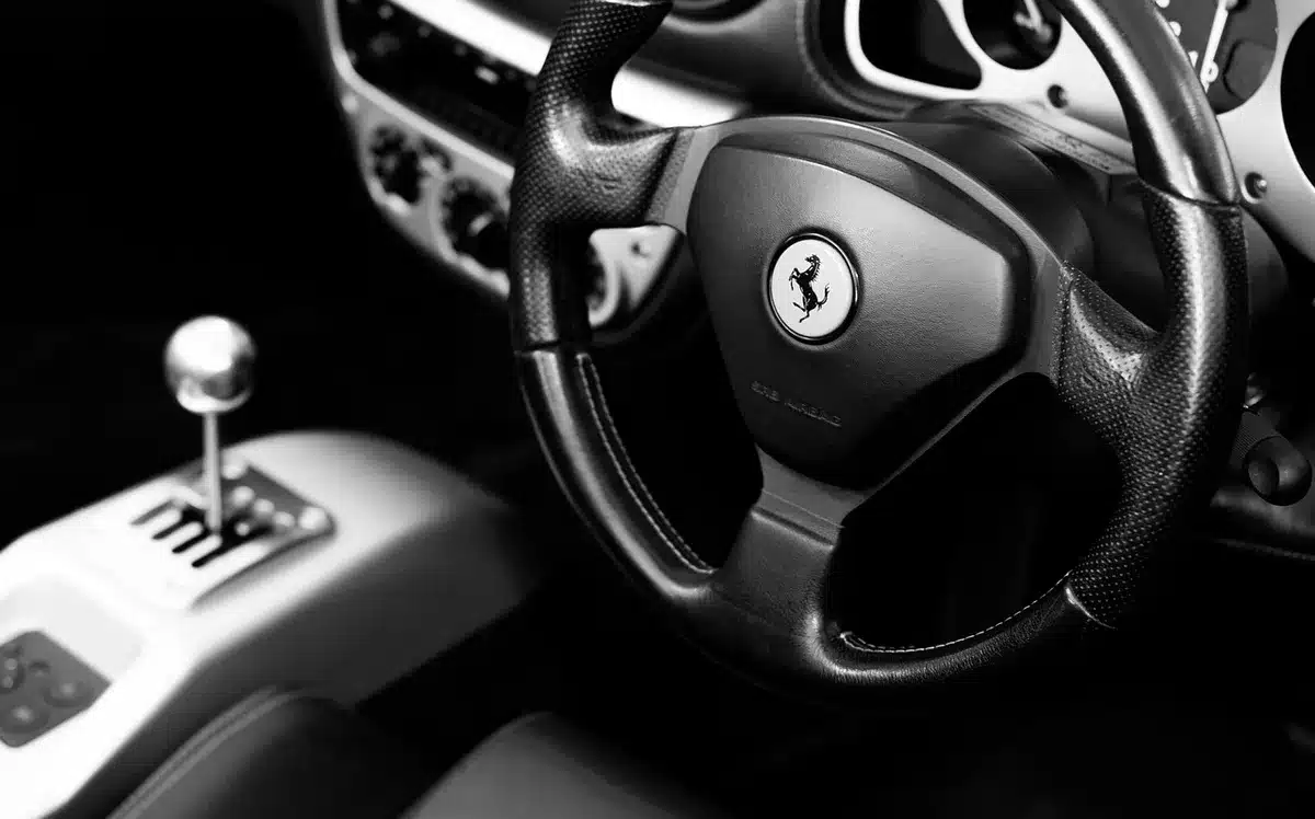Anonymous pair of hands gripping a steering wheel, dashboard showing empty fuel gauge, highway ahead blurred