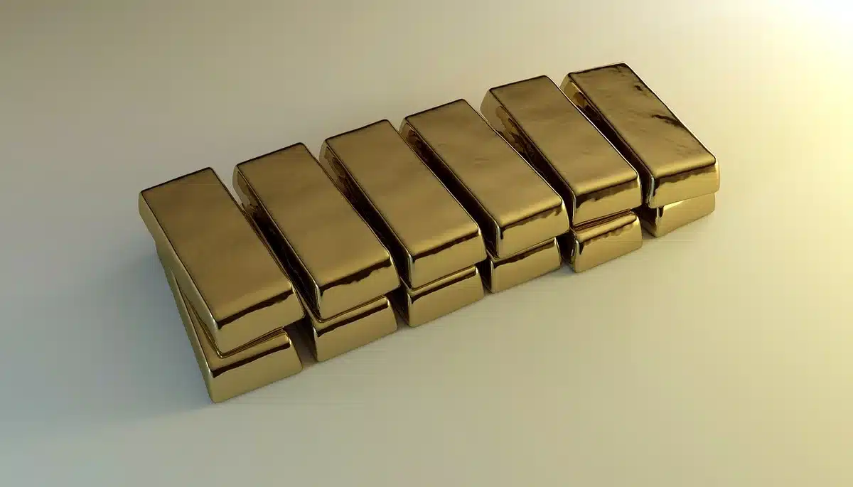A close-up of an unbranded metal bullion resting on a plain wooden table, soft reflections on its surface and shallow depth of field suggesting value; no logos or text
