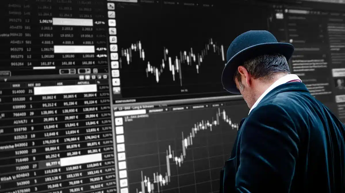 Close-up of anonymous hands pointing at a laptop showing a muted stock chart and chip diagram, office desk, no brand visible